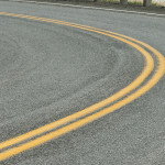 Close view of a sharp left curve on a rural roadway.